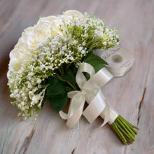 A wedding bouquet of artificial faux silk roses edged with Gypsophila