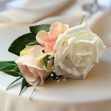 A corsage featuring blush pink and ivory roses