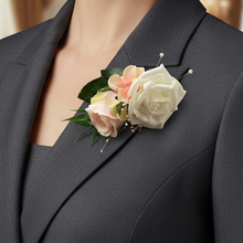 A corsage featuring blush pink and ivory roses