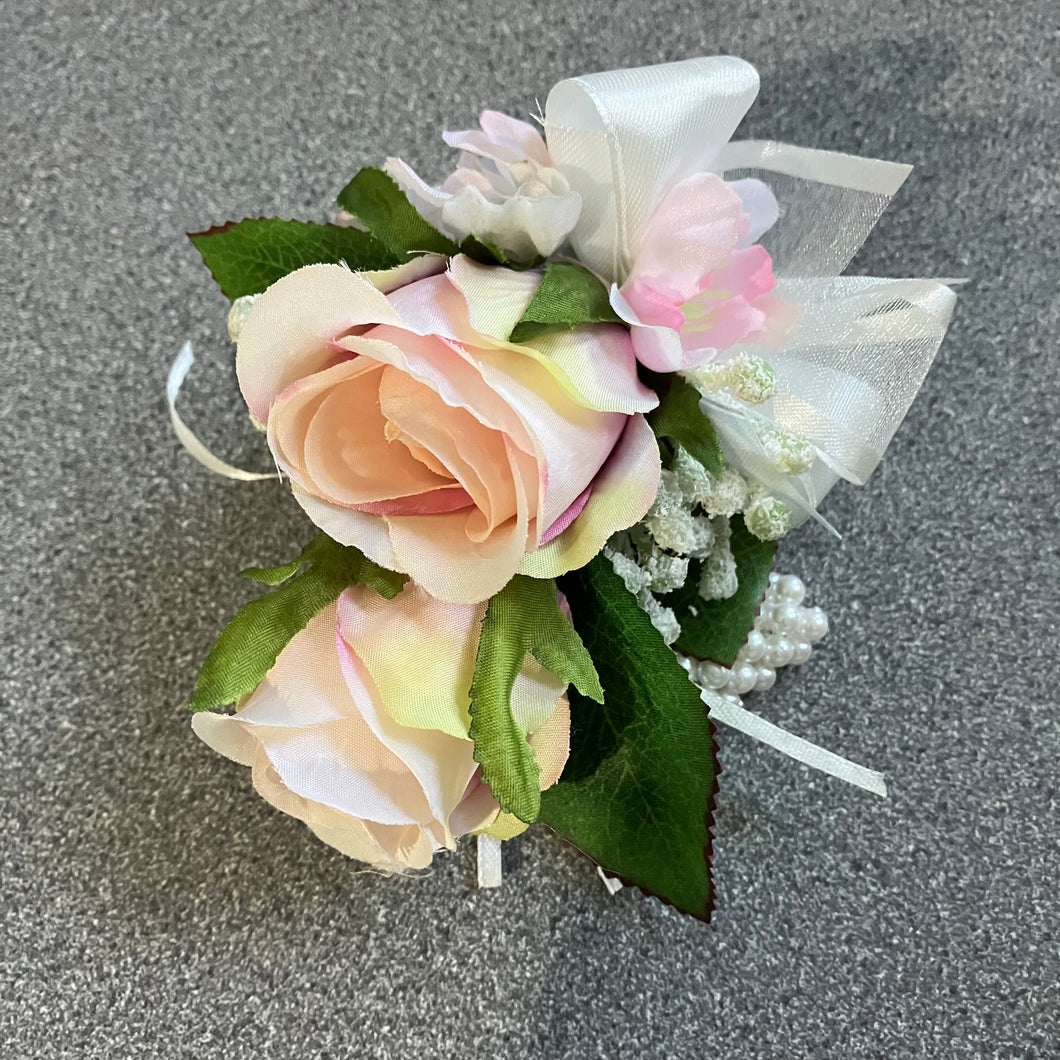 wrist corsage features blush pink silk rose flowers on pearl bracelet