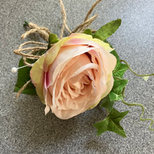 A wedding buttonhole featuring a blush pink silk rose and ivy