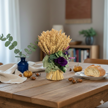 A dried handtied bunch of wheat with purple flower arrangement