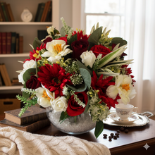 An arrangement of red and ivory flowers displayed in glass fish bowl