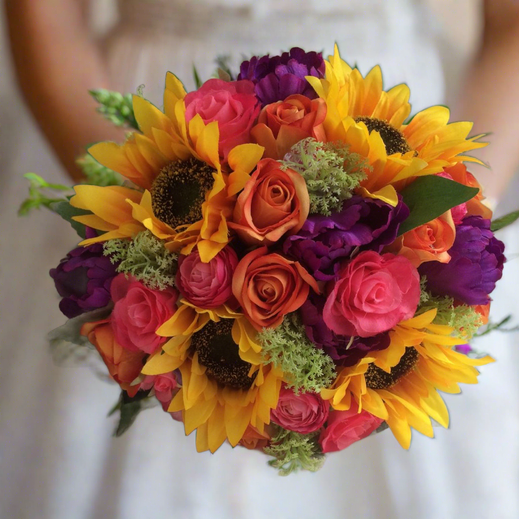 a brides bouquet of sunflowers roses, ranunculus and tulips