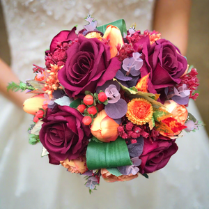 A wedding bouquet of artificial silk burgundy & orange flowers