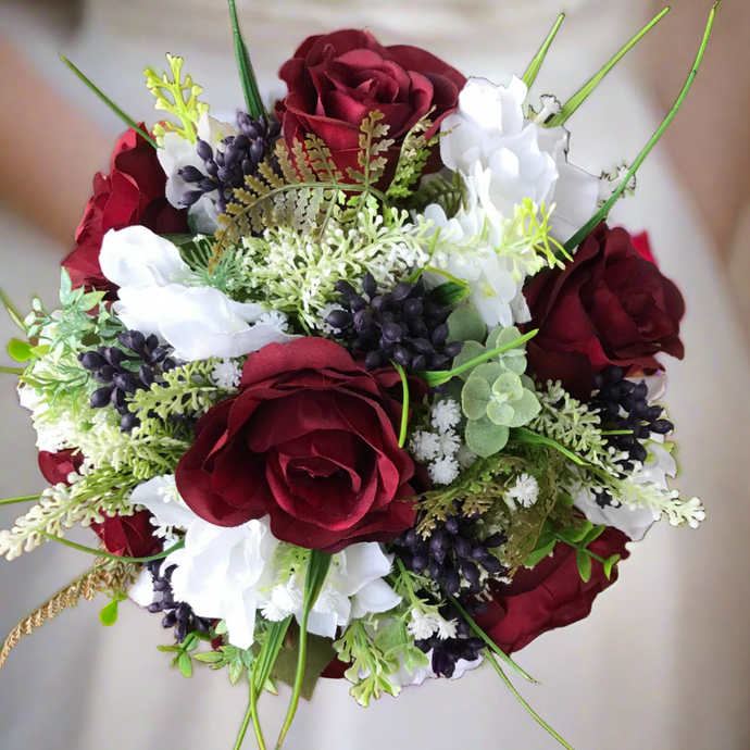 A wedding bouquet of artificial silk burgundy & ivory flowers, foliage & berries