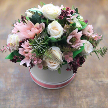 An arrangement of peach and burgundy flowers in cream hat box