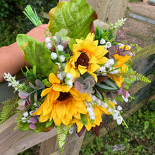 A wedding bouquet of artificial sunflowers and lily of the valley