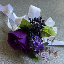 A bridal bouquet of white, black, purple artificial flowers