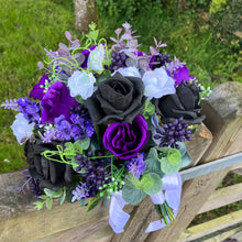 A bridal bouquet of white, black, purple artificial flowers