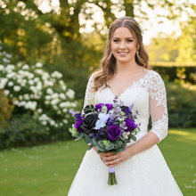 A bridal bouquet of white, black, purple artificial flowers