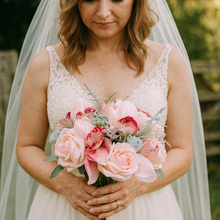 A wedding bouquet of coral and grey artificial roses and orchids