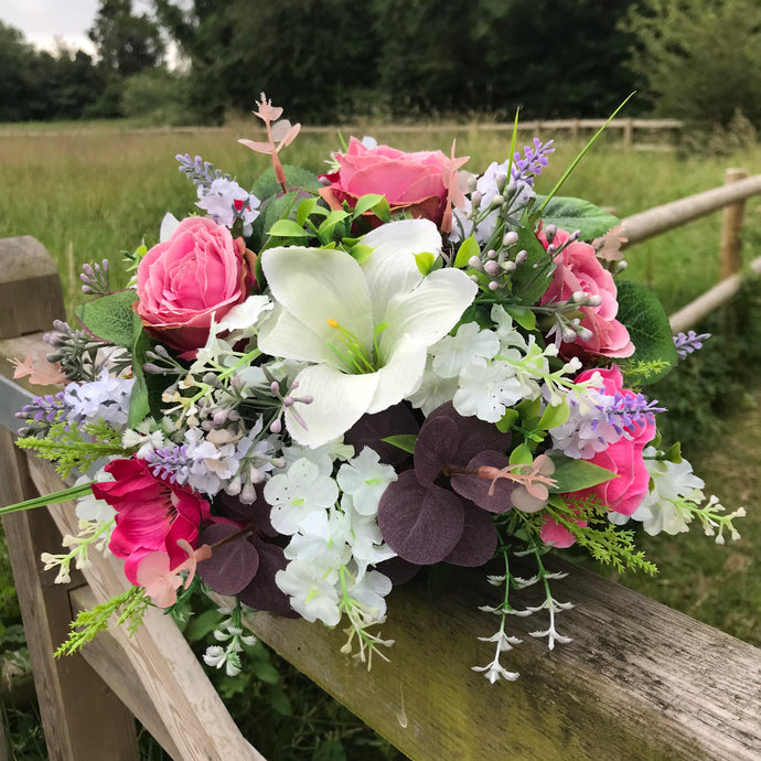 A table centre featuring artificial pink and cream flowers