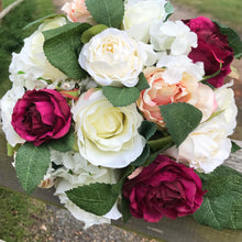 A wedding bouquet of peach, ivory and burgundy silk roses