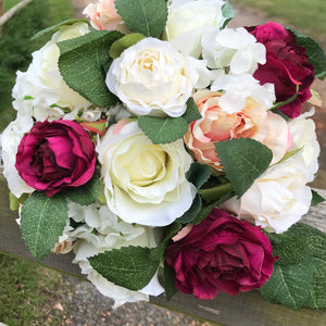 A wedding bouquet of peach, ivory and burgundy silk roses