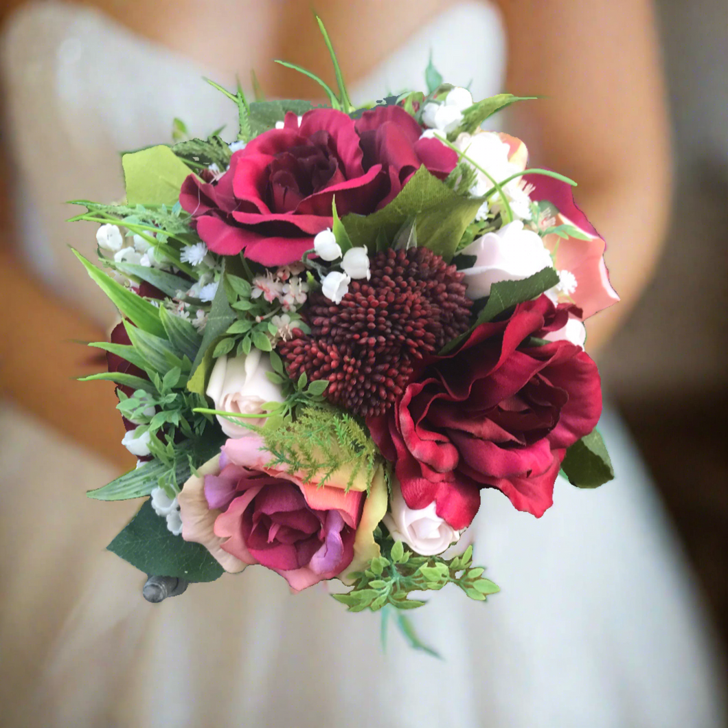 A wedding bouquet of artificial burgundy and pink roses