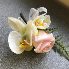 A buttonhole featuring a pink rose and orchid