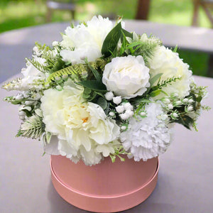 A posy arrangement of silk flowers in hat box