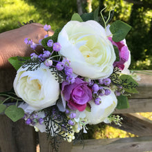 A brides bouquet of pink and lilac artificial silk flowers