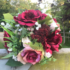 A wedding bouquet of artificial burgundy and pink roses