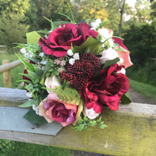 A wedding bouquet of artificial burgundy and pink roses