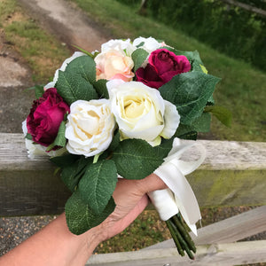 A wedding bouquet of peach, ivory and burgundy silk roses