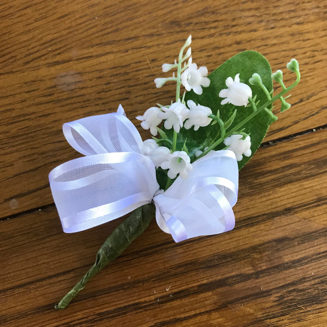 a buttonhole featuring artificial lily of the valley flowers