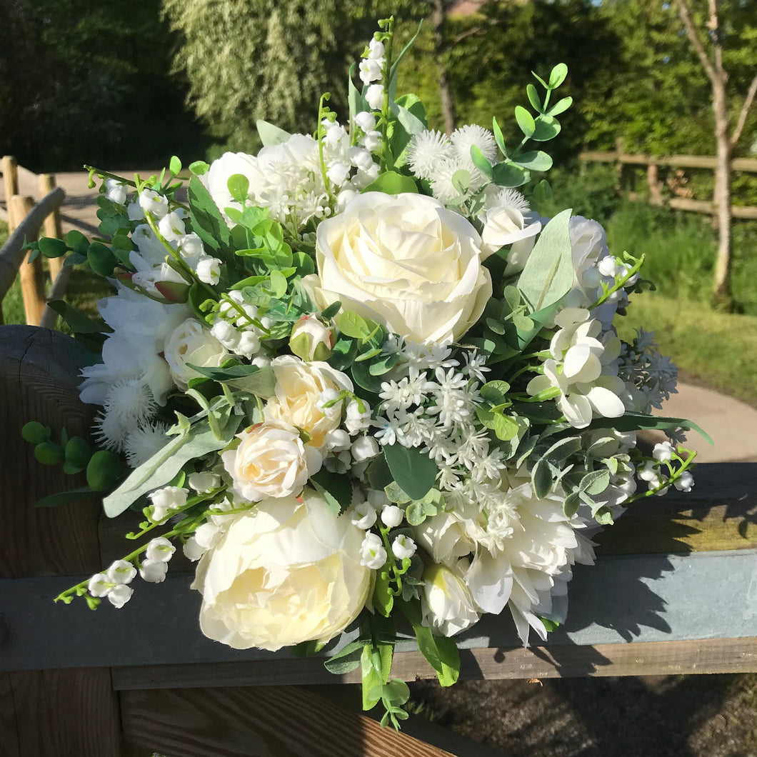A brides bouquet featuring white ivory artificial flowers
