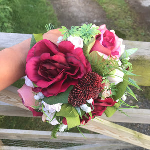 A wedding bouquet of artificial burgundy and pink roses
