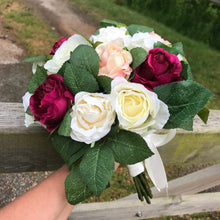 A wedding bouquet of peach, ivory and burgundy silk roses