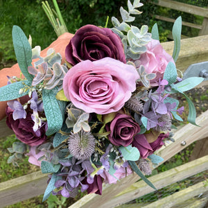 A wedding bouquet of artificial mauve/pink and burgundy roses