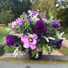 A purple and lilac memorial flower arrangement in black plastic pot