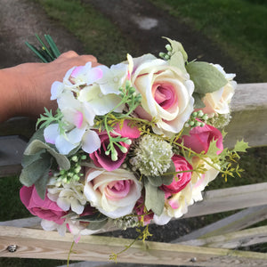 a brides bouquet of roses, waxflower and ranunculas