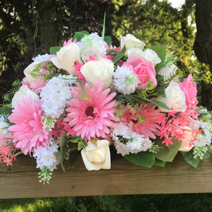 An artificial top table flower arrangement of pink and ivory roses and gerbera