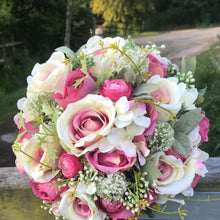 a brides bouquet of roses, waxflower and ranunculas