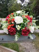 A flower arrangement of ivory orange and red flowers