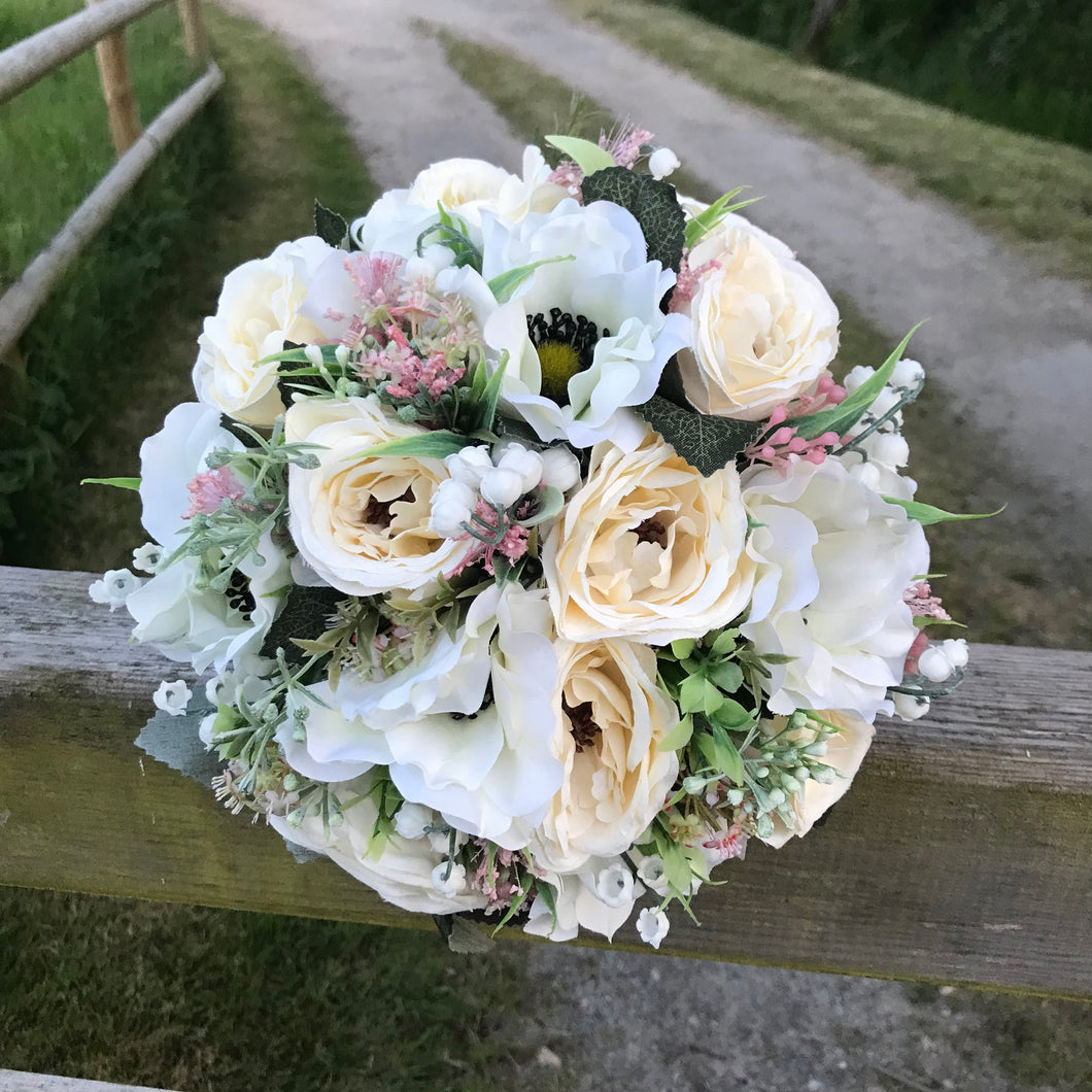 A brides bouquet of artificial cream ranunculus and anemone flowers