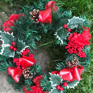 an artificial pine christmas wreath with cones and berries