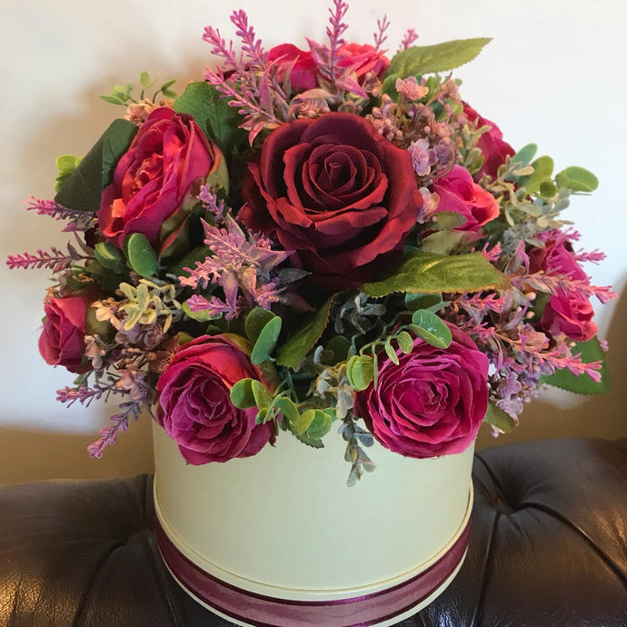 burgundy and raspberry roses arranged in a hat box