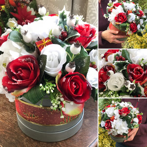 A Christmas flower arrangement featuring artificial white and red roses
