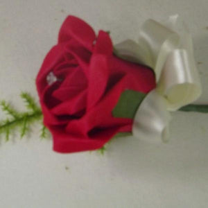 artificial buttonhole features a single red rose, ribbon bow,asparagus fern
