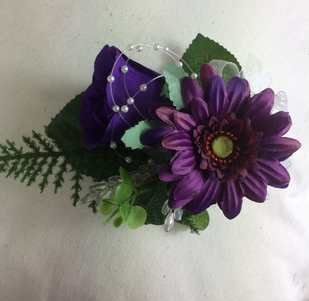 an artificial flower corsage of a purple rose and gerbera