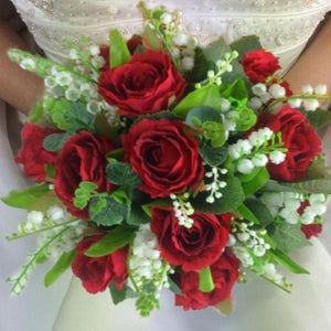 a wedding bouquet of red silk roses and white lily of the valley