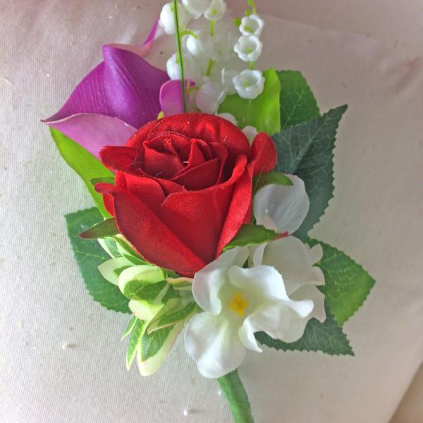 artificial corsage of red and violet flowers