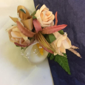 An artificial corsage of foam roses and calla lily