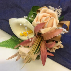 An artificial corsage of foam roses and calla lily