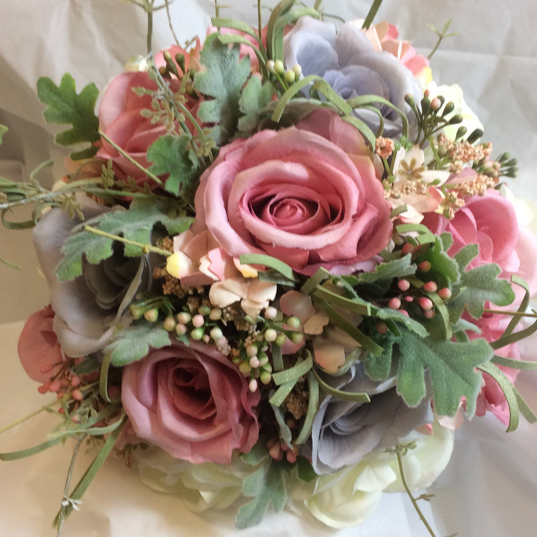 a brides bouquet of dusky pink, lavender/grey and ivory roses