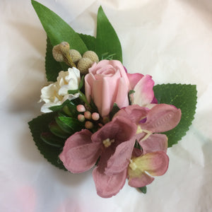 An artificial corsage of pink roses and foliage