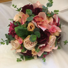 A brides bouquet featuring burgundy, peach & blush pink flowers