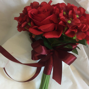 A bridesmaid bouquet or red artificial silk roses and hydrangea